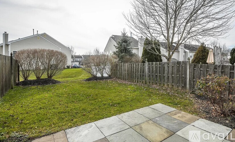 A backyard with a wooden fence and a stone patio.