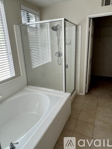 A white bathtub with a glass shower door in a bathroom.