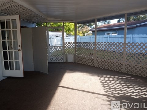 A sunny backyard with a lattice fence and a carport.
