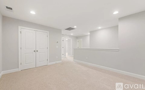 A spacious room with white walls and a carpeted floor.