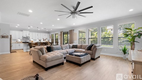 A spacious living room with a large sectional sofa and a ceiling fan.