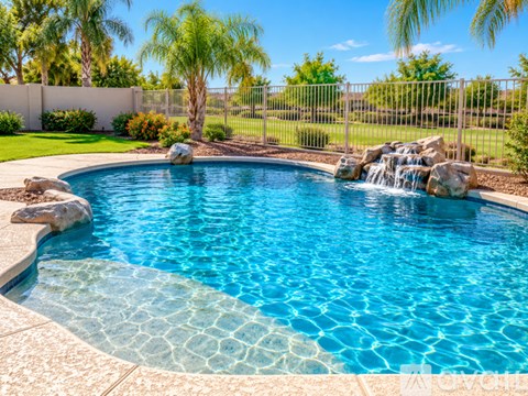 A small pool with a waterfall and a stone border.