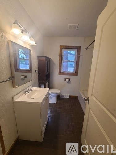 A bathroom with a toilet, sink, and mirror.