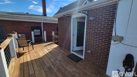 A wooden deck with a white railing and a brick building.