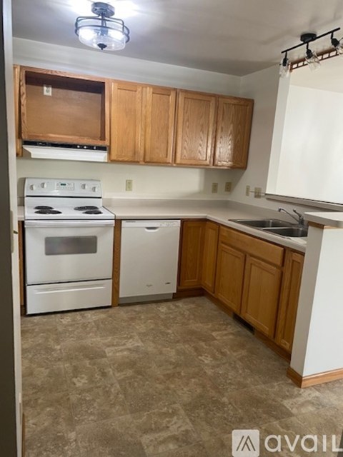 A kitchen with white appliances and wooden cabinets.