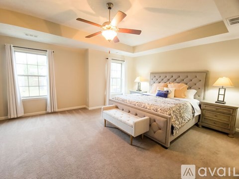 A bedroom with a large bed, a bench, and a ceiling fan.