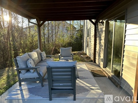 A patio with a couch and a chair under a roof.