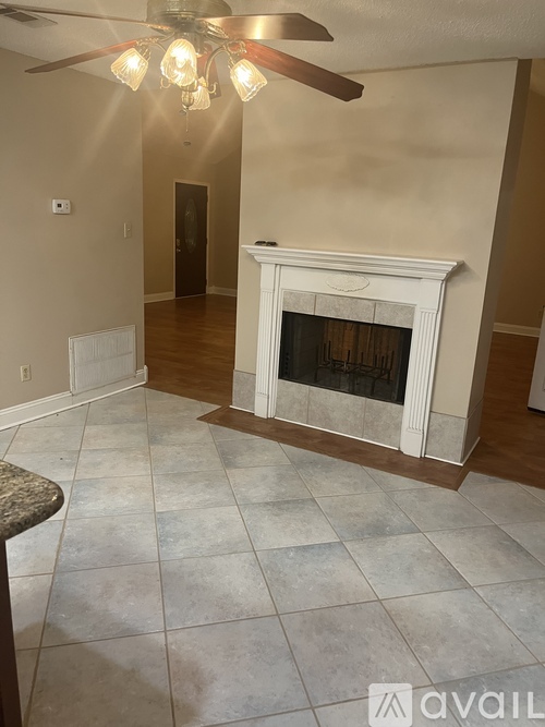 A living room with a fireplace and a ceiling fan.