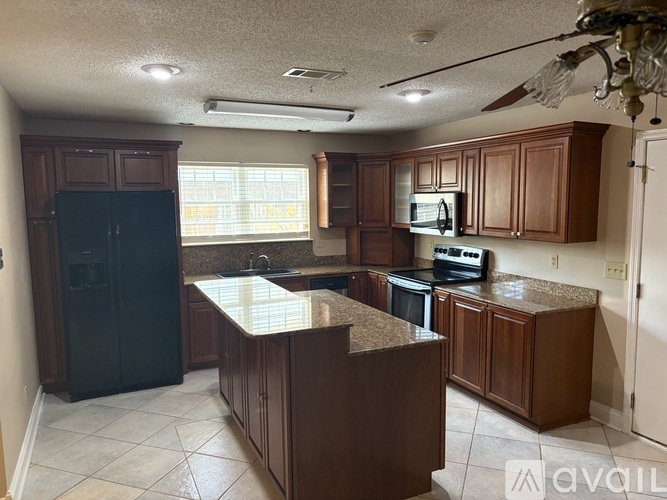 A kitchen with brown cabinets and a black refrigerator.