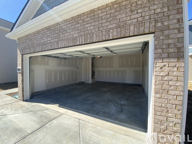 A garage door is open, revealing a clean, empty garage space.