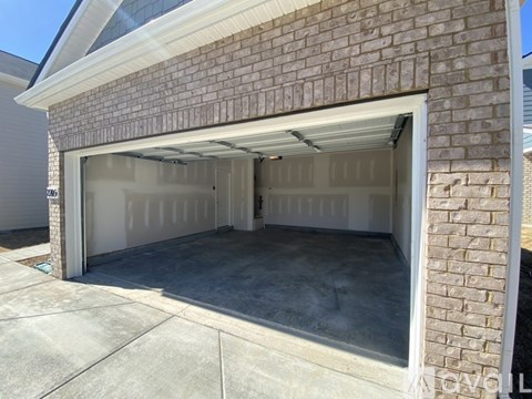 A garage door is open, revealing a clean, empty garage space.