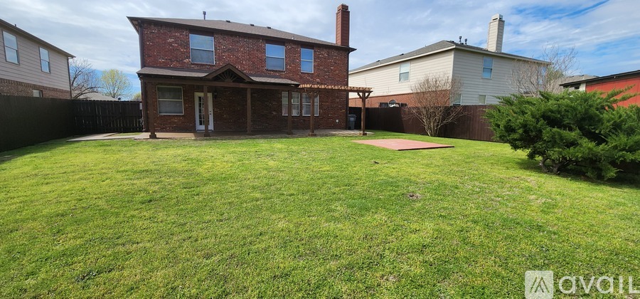 A red brick house with a white fence and a green lawn in front.
