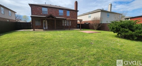 A red brick house with a white fence and a green lawn in front.