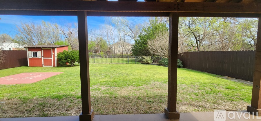 A backyard with a red building and a fence.