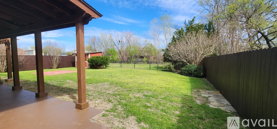 A backyard with a fence and a covered patio.