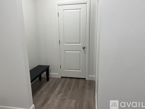 A white door with a black bench in front of it.