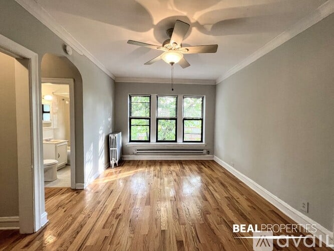 A spacious room with wooden floors and a ceiling fan.