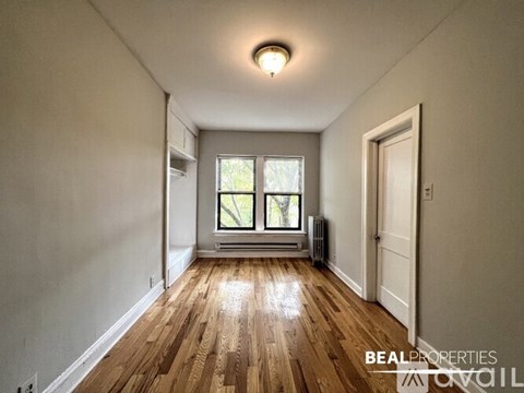 A room with wooden floors and a window with a view of trees.