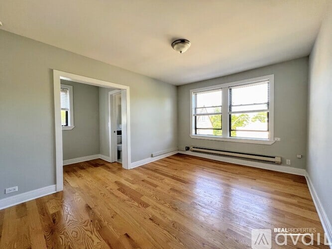 A room with wooden floors and a window with a view of trees.