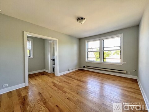 A room with wooden floors and a window with a view of trees.