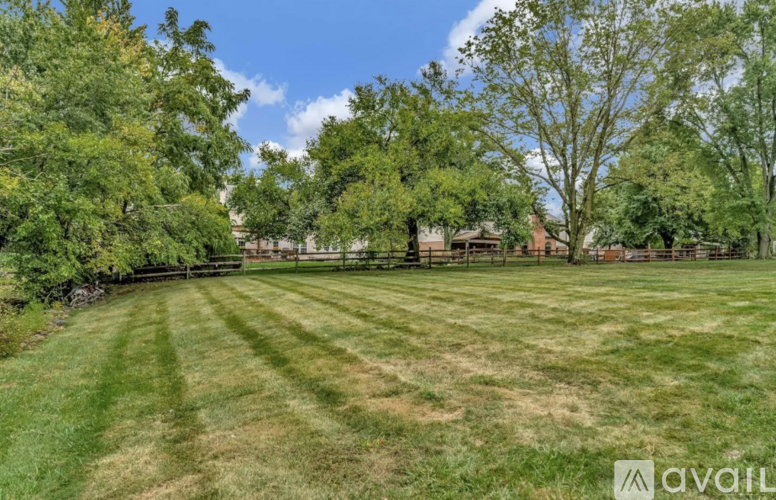 A large, well-maintained lawn with trees and a fence in the background.
