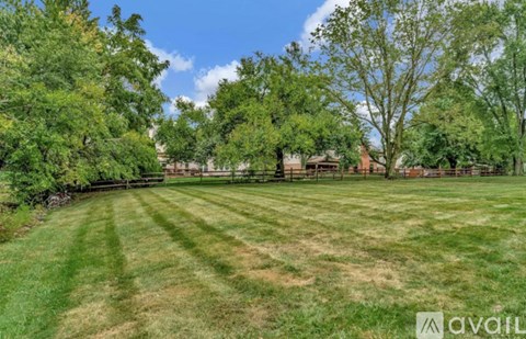 A large, well-maintained lawn with trees and a fence in the background.