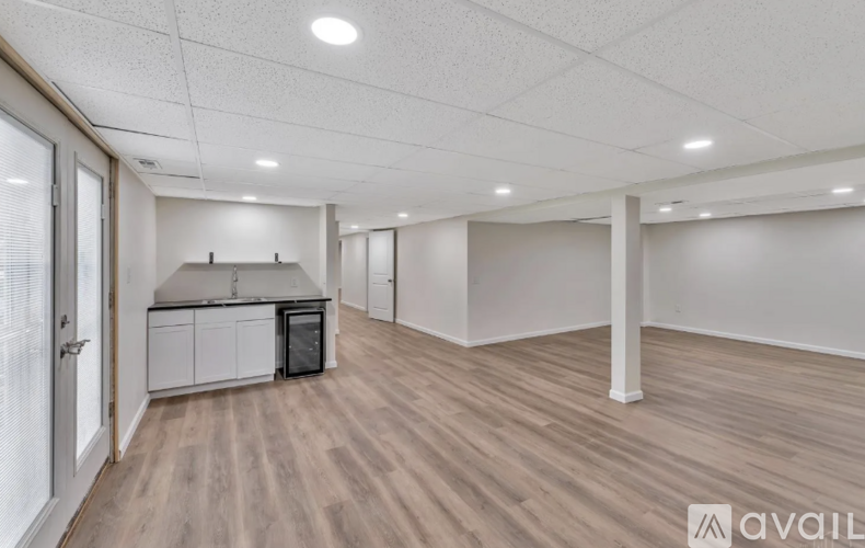 A spacious room with wooden flooring and white walls.