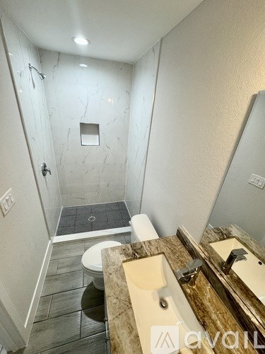 A bathroom with a marble shower and a toilet.