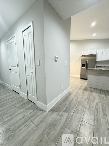 A kitchen area with a refrigerator, cabinets, and a countertop.