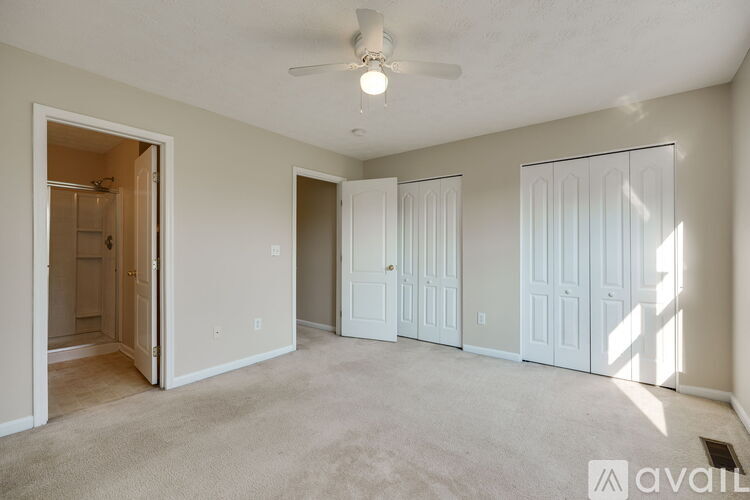 A spacious room with a ceiling fan and three doors.