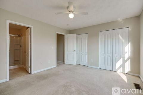 A spacious room with a ceiling fan and three doors.