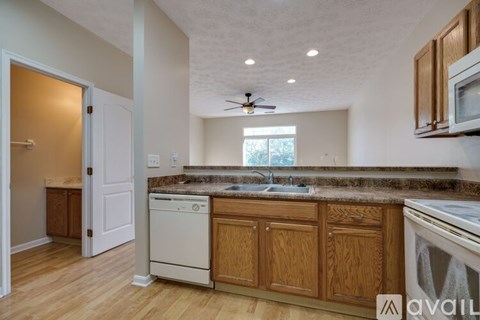 A kitchen with wooden cabinets and a white dishwasher.
