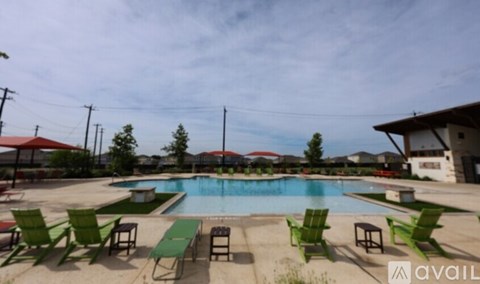A pool surrounded by green chairs and tables.