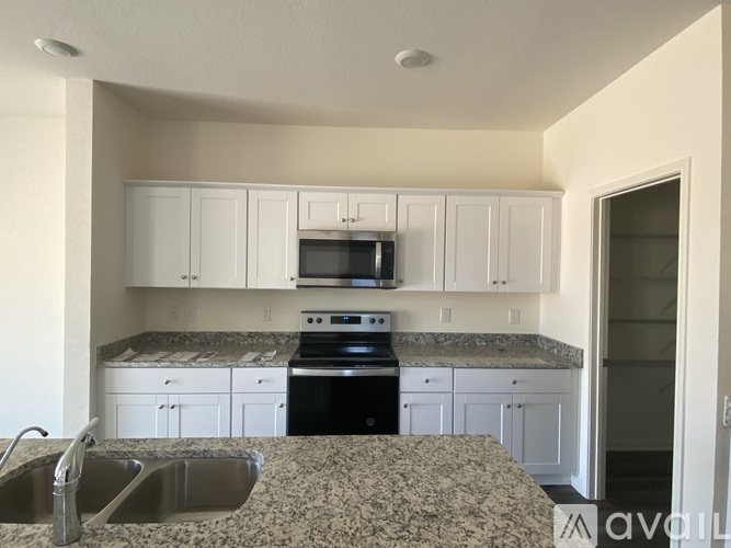 A kitchen with granite countertops and white cabinets.