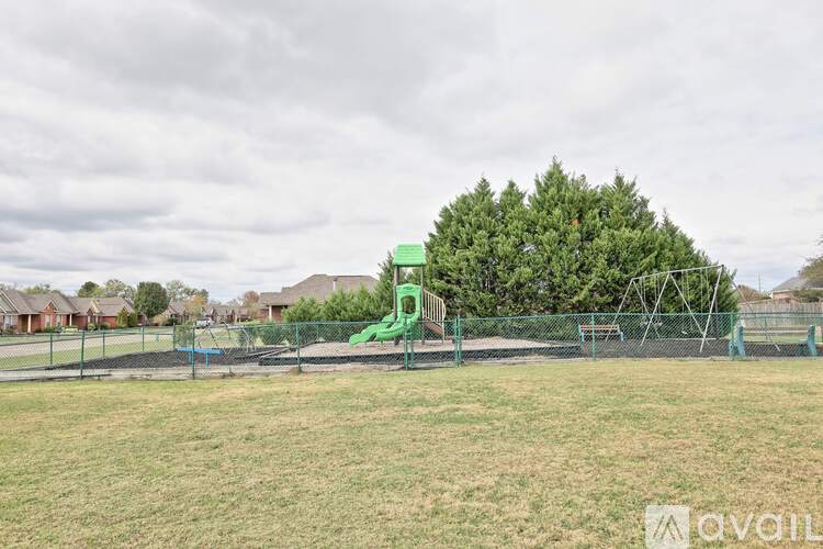 A playground with a green slide and a fence.