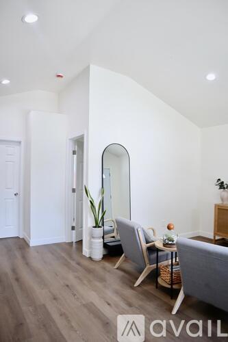 A living room with a grey sofa, a wooden table, a mirror, and a potted plant.