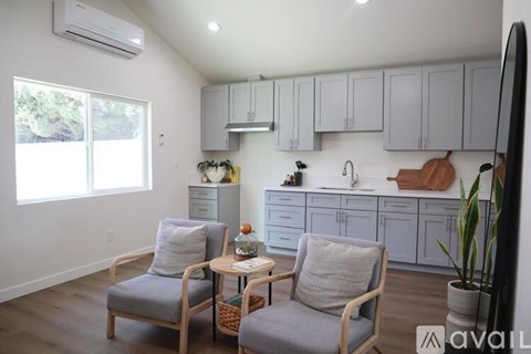 A living room with two chairs and a table in front of a kitchen.
