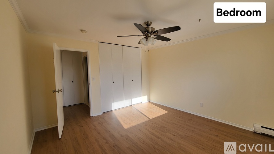 A bedroom with a ceiling fan and light, and a doorway leading to another room.