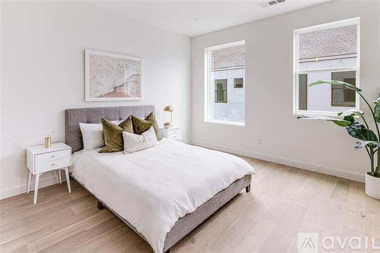 A bedroom with a large bed, a nightstand, and a plant.