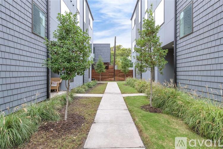 A pathway leads through a small garden between two buildings.