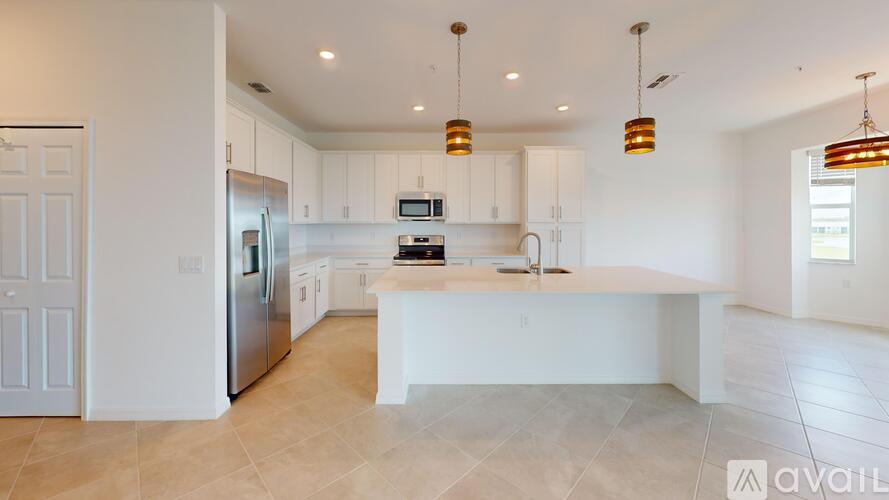 A modern kitchen with a central island and pendant lights.