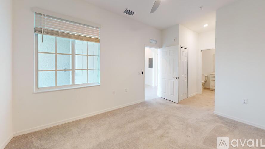 A spacious room with a window and a door leading to another room.