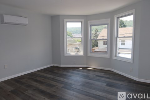 A room with a wooden floor and three windows.