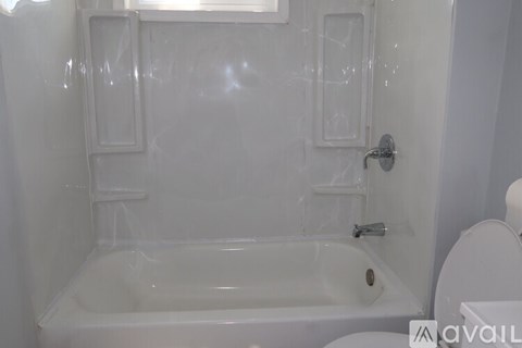 A white bathroom with a tub and toilet.