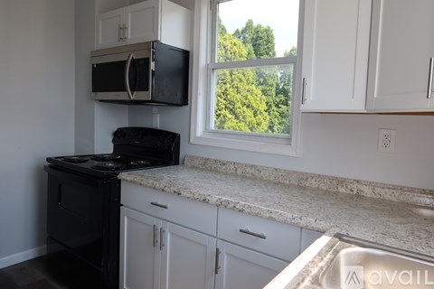 A kitchen with black appliances and white cabinets.