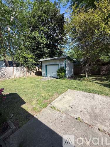 A backyard with a shed and a concrete slab.