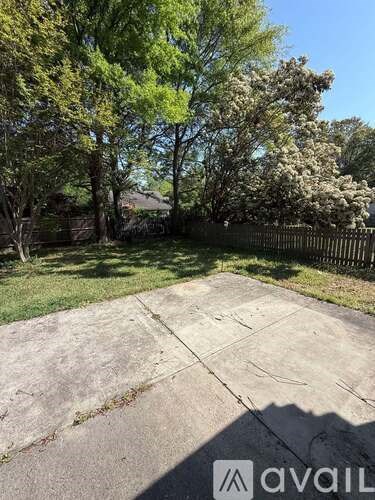 A concrete area surrounded by trees and a fence.