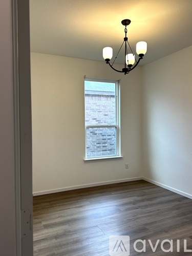 A room with a chandelier and a window with a view of a building.