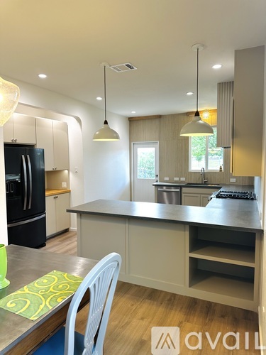 A kitchen with a black fridge and a table with a green mat on it.