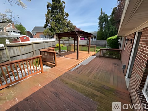 A wooden deck with a pergola and a hot tub.
